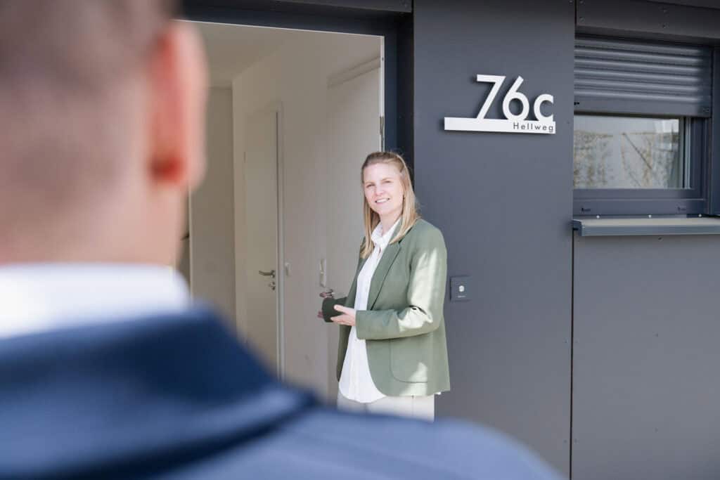 Beraterin empfängt einen Interessenten an der Haustür